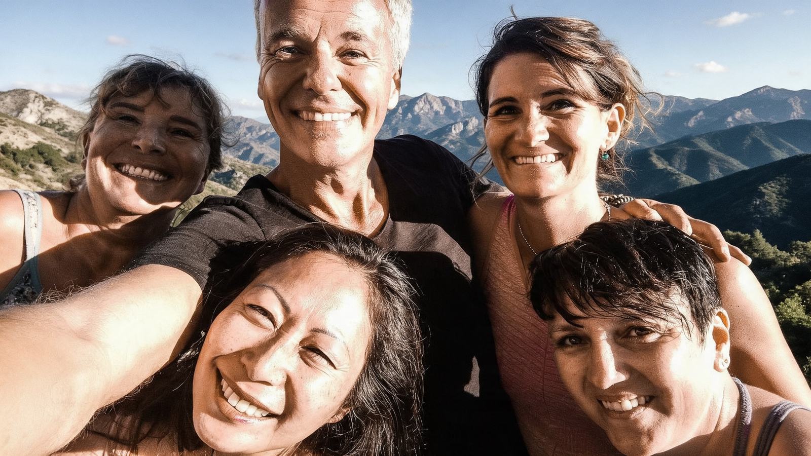 Stefan Geisse mit lachenden Teilnehmerinnen vor einem Bergpanorama