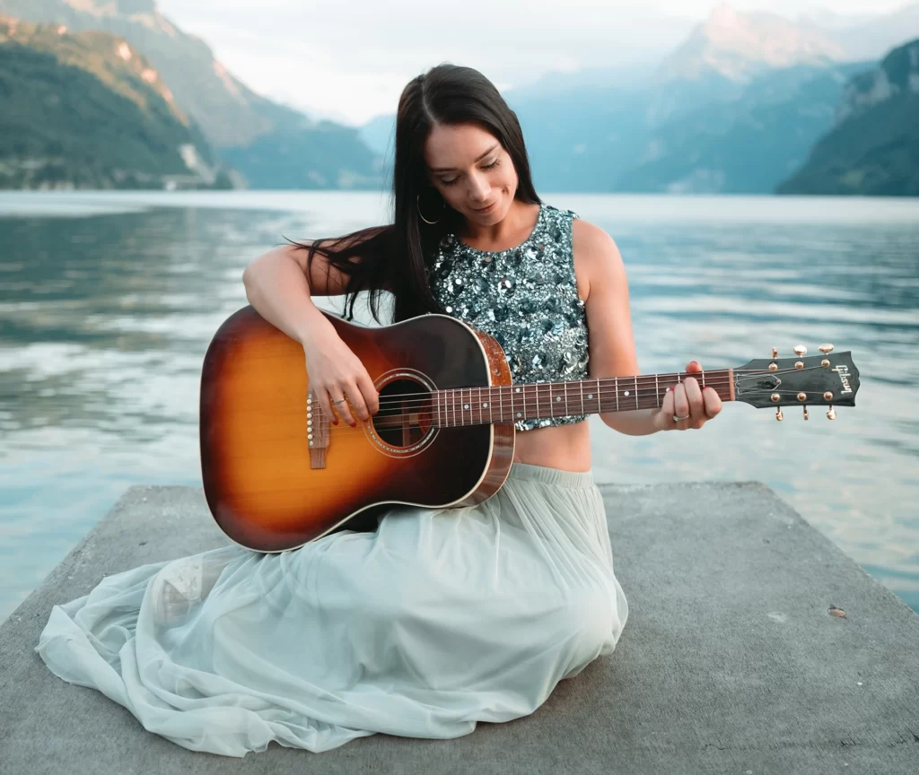 Frau spielt Gitarre am See
